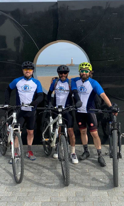 Three men standing next to their bikes and wearing CHECT cycling jerseys, sunglasses and helmets. 