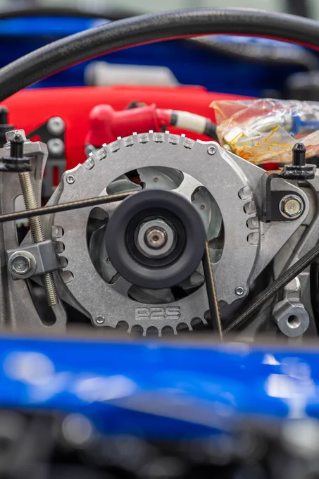 Tight shot of Prodrive P25 engine components with exposed pulley system, belts and machined aluminium parts, capturing the mechanical detail and motorsport engineering behind the car