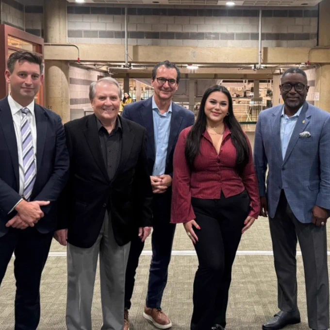 Professionals standing together in a professional setting and smiling at the camera. 