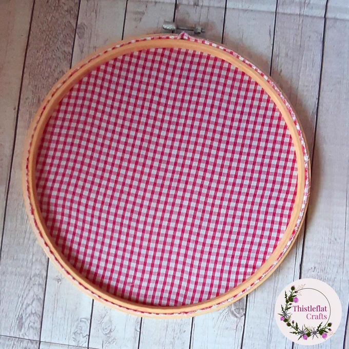 Back of an embroidery hoop backed with pink and white gingham fabric