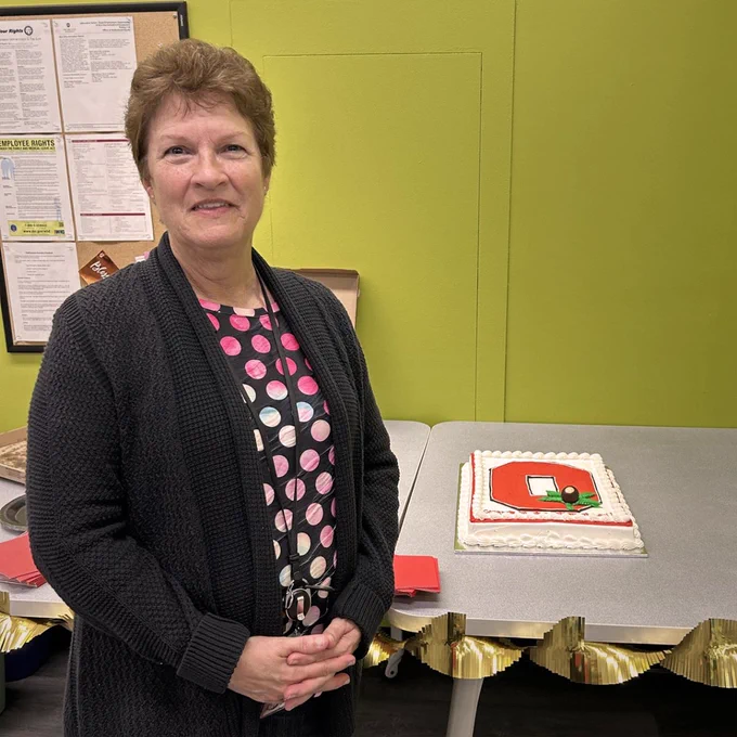 Lori Stevens smiling, next to her retirement cake.