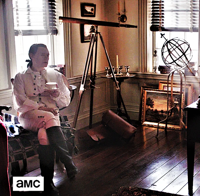 Burn Gorman as Major Edmund Hewlett sitting coatless in his New York office with his astronomical instruments in the background. TURN: Washington's Spies E 407