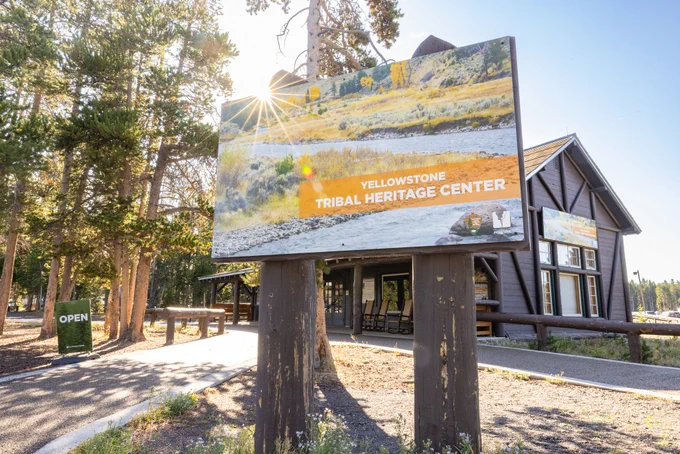 A large wooden sign in front a building that reads "Yellowstone Tribal Heritage Center"