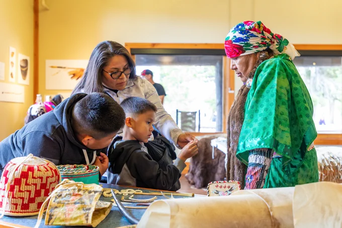 An Indigenous presenter showing visitors a variety of tools