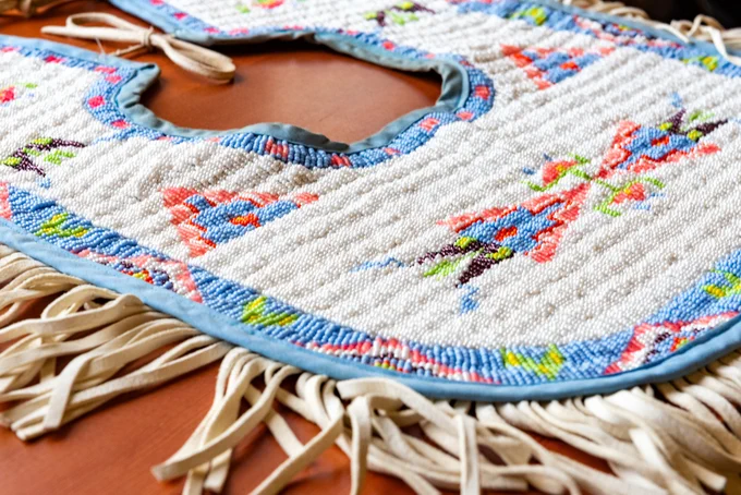 A close-up of an intricately beaded collar/bib with fringe 