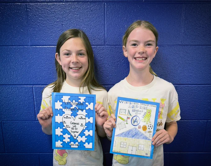 Two students hold copies of the yearbook featuring their winning cover designs