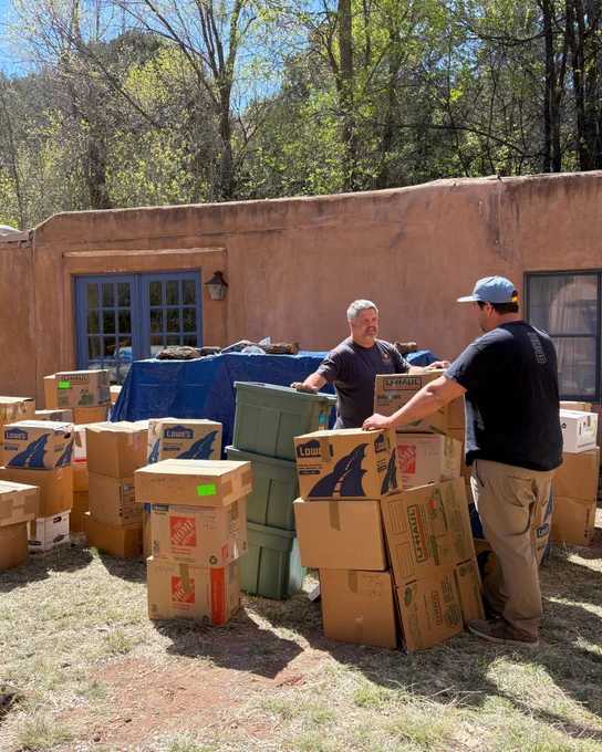 Two individuals stand among dozens of boxes of books outside Cormac McCarthy’s home in Santa Fe, New Mexico.