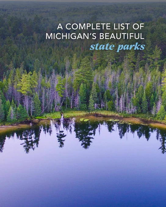 Aerial view of a calm lake reflecting a dense forest with overlay text reading, A complete list of Michigan\u2019s beautiful state parks