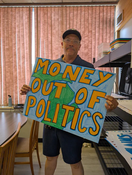 Holding a sign reading "Money Out Of Politics" 