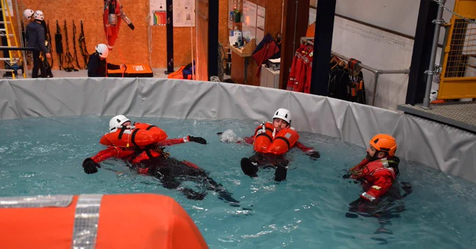 Three people in a sea survival tank.