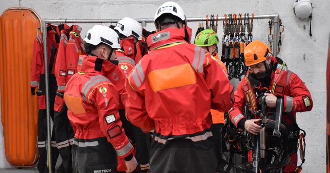 Five people getting suited up in harnesses.