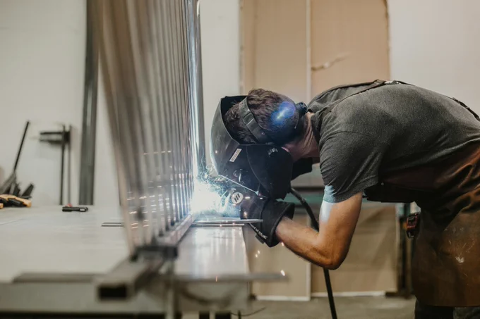 A person dressed in protective clothing welding in a workshop.