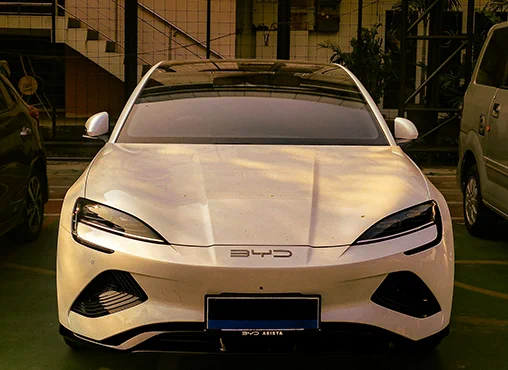 Front view of a sleek white BYD electric car parked indoors with tinted windows and modern headlights.