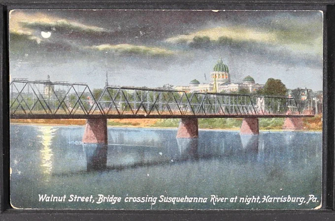 Illustrated post card of a metal bridge with the city of Harrisburg in the background.  Text at the bottom reads "Walnut Street, Bridge crossing Susquehanna River at night, Harrisburg, Pa"