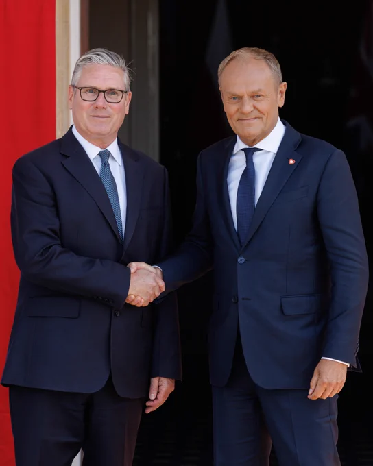 Donald Tusk and Keir Starmer shake hands.