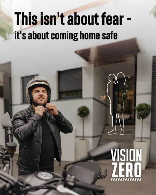 A person wearing a helmet stands next to a motorcycle in front of a building entrance with text overlay: "This isn't about fear - it's about coming home safe." The image includes the Vision Zero logo.
