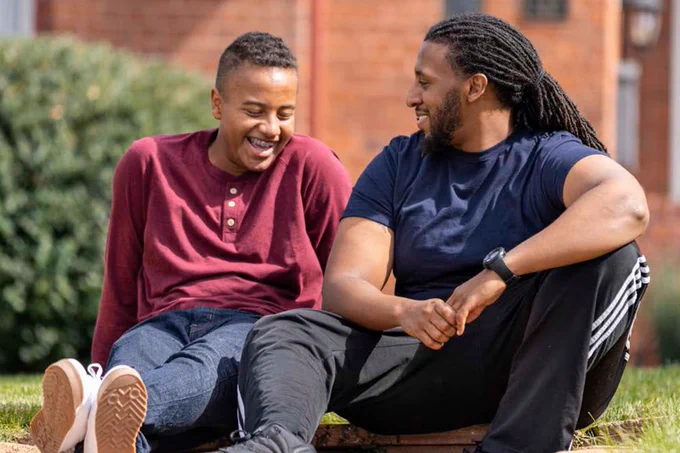 Two individuals sit outside talking at the Big Brothers Big Sisters mentorship program