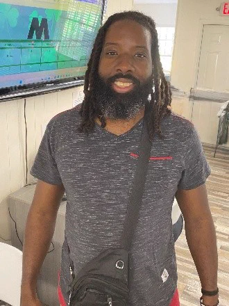 Gentleman standing in front of television wearing grey tee shirt 