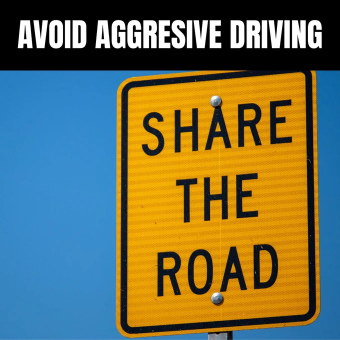 Image of a yellow road sign with the text "Share the Road" is displayed against a clear blue sky. Above the sign, a black banner that reads Avoid Aggressive Driving.