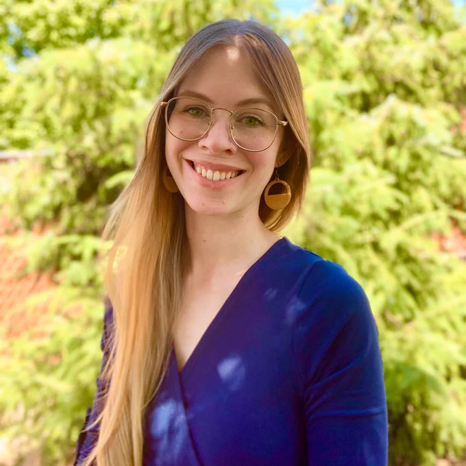 Headshot of the new Entrepreneurship Librarian, Bridget Wipf,  standing outside surrounded by vibrant greenery.