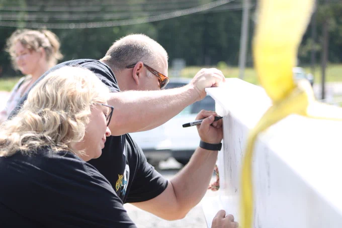 Attendees sign the ceremonial steel beam during the Joe T. Robinson High School topping out ceremony.