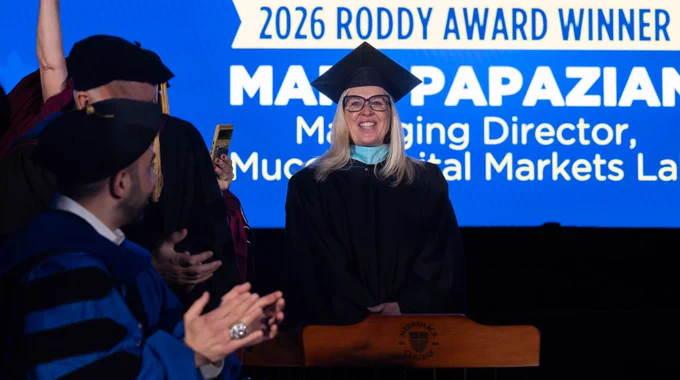 Mary Papazian smiles and stands on stage during Commencement.