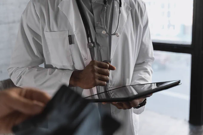 A professional medical practitioner holding a tablet, focused on work in a clinical setting.