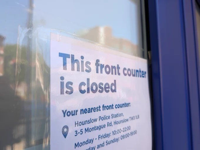 Sign on a glass door stating 'This front counter is closed' with details of Hounslow Police Station.