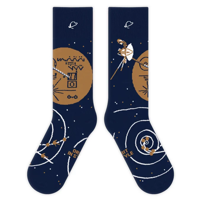 Socks inspired by the Voyager mission. Left shows the Voyager Golden Record disc, right shows the Voyager spacecraft and the two spacecraft trajectory lines across the solar system. Socks are blue, brown/gold and white.