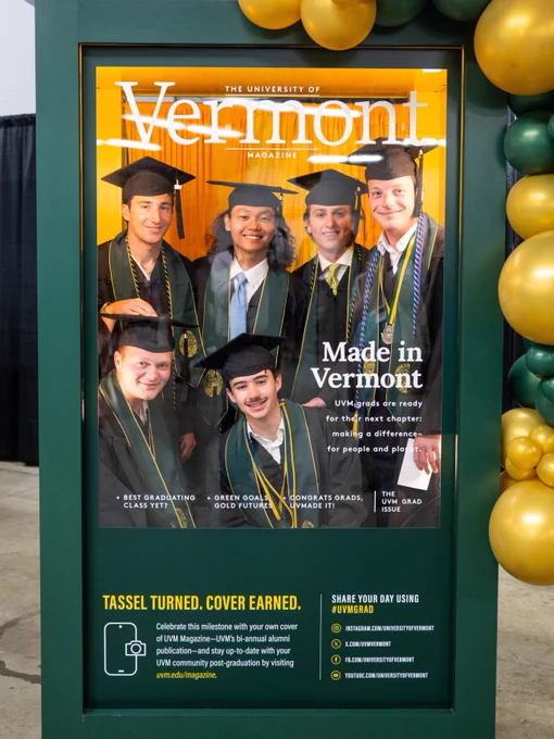 This image is the cover of The University of Vermont magazine. It features a group of graduates in caps and gowns smiling at the camera. The headline reads "Made in Vermont." Green and gold balloons decorate the sides of the magazine stand.