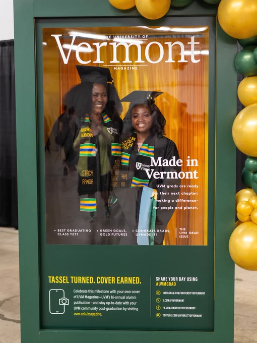 A magazine cover titled "University of Vermont Magazine" features two people wearing graduation attire and colorful stoles. They are smiling and standing in front of a gold curtain. Text on the cover reads "Made in Vermont" and highlights graduate achievements. Balloons are visible on the side.
