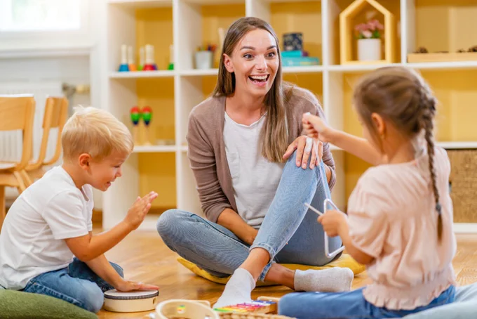 A speech language pathologist works with two young children in a well lit clinic space