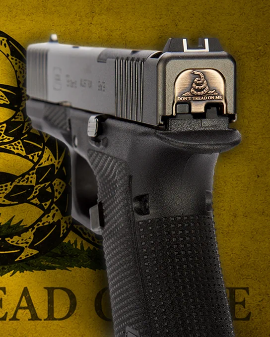 Brass rear slide plate engraved with a coiled rattlesnake and the words “Don’t Tread On Me,” displayed against a yellow Gadsden flag background.