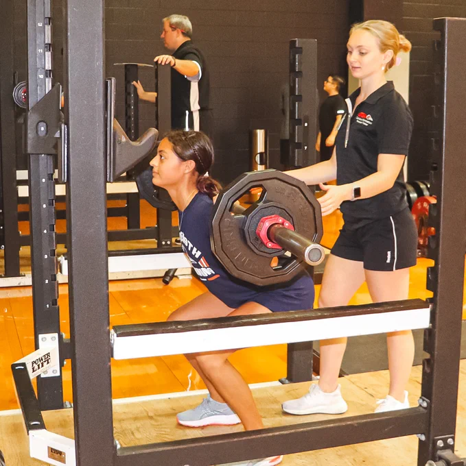 Personal Trainer spotting a participant of the Youth Performance Program doing a squat