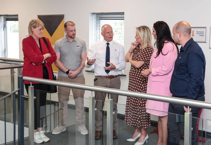 Image of 6 people standing talking – First Minister Michelle O’Neill and deputy First Minister Emma Little-Pengelly pictured during their visit to On Track Technicians, an engineering company in Lisburn.