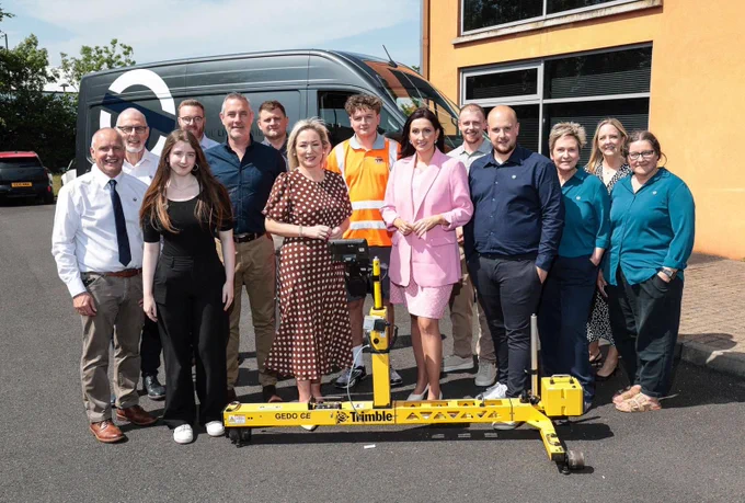 Image of 14 people standing behind engineering equipment – First Minister Michelle O’Neill and deputy First Minister Emma Little-Pengelly pictured the owners and staff during their visit to On Track Technicians, an engineering company in Lisburn.