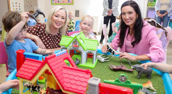 Image of 4 people sitting playing – First Minister Michelle O’Neill and deputy First Minister Emma Little-Pengelly pictured playing with children during their visit to Kids Korner Day Nursery in Belfast.