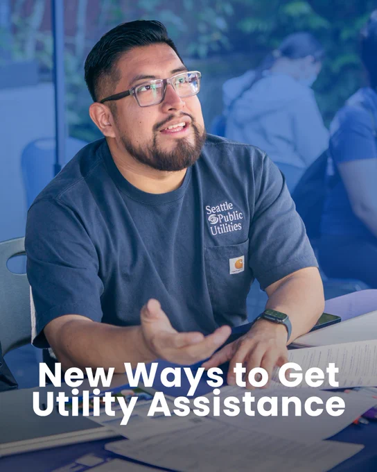 A person wearing a “Seattle Public Utilities” shirt sits at a table with papers, gesturing while speaking. The text on the image reads, “New Ways to Get Utility Assistance.”