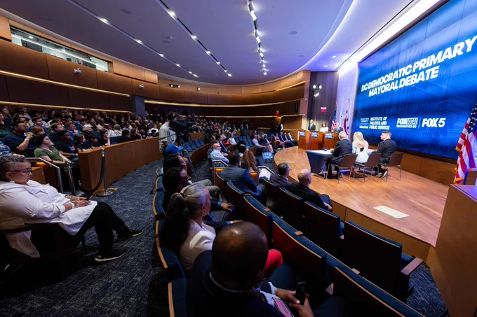 a live audience watches a debate on a stage