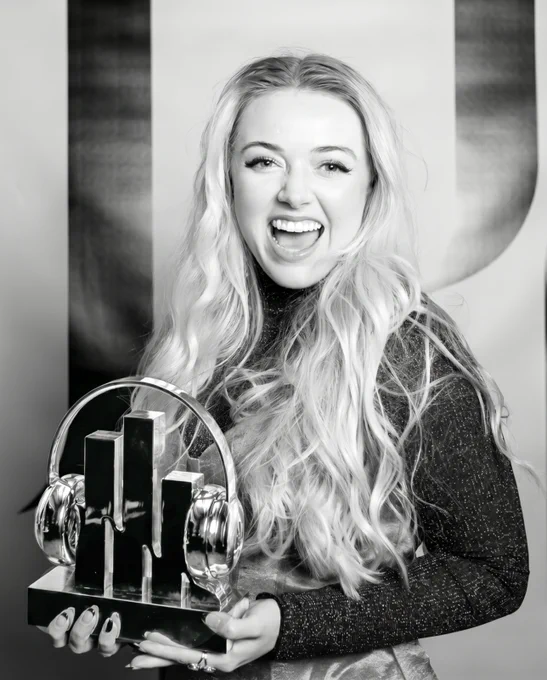 A joyful individual with long hair holding a stylish music award shaped like headphones. The scene is bright and engaging.