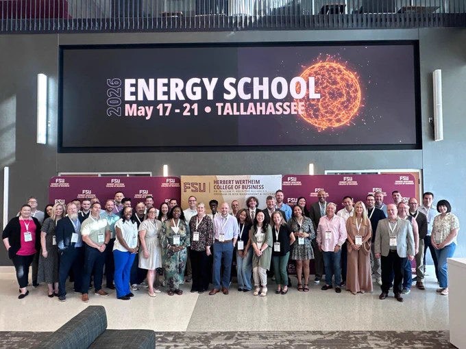 A group of people posing for a photo in front of a sign for the 2026 Energy School event in Tallahassee, hosted by the FSU Herbert Wertheim College of Business.