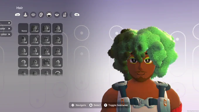Image of medium-brown skinned person with very full light green and dark green afro. Person has eyeshadow and a close shaved beard. 