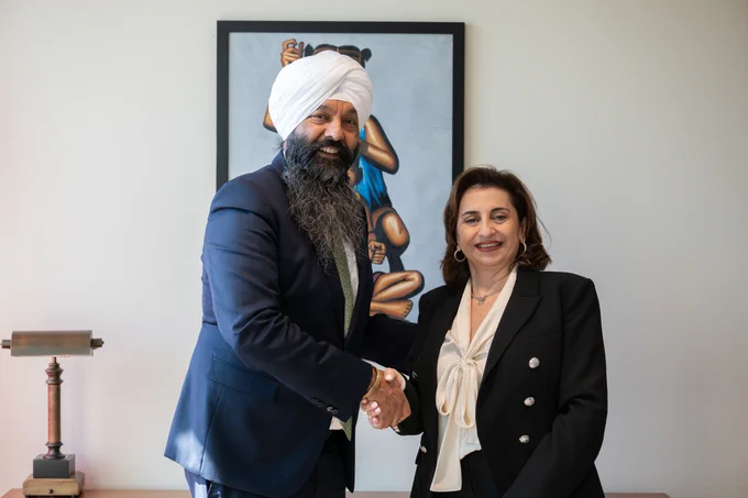 Secretary of State Randeep Sarai stands next to UN Women Executive Director Sima Bahous. They are facing the camera shaking hands, smiling.