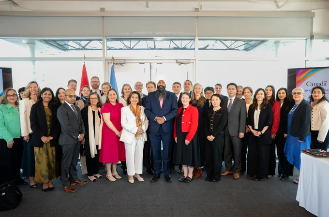 A large of people is gathered facing the camera smiling with Secretary of State Sarai in the middle.