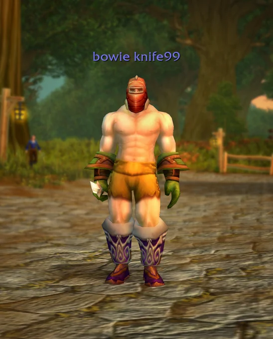 In the center of the image is a partially clothed human male. He wears a mask, gauntlets, shorts, and red boot.s Above him is the text \"bowie knife99\" in purple. In the background is a forest clearing.