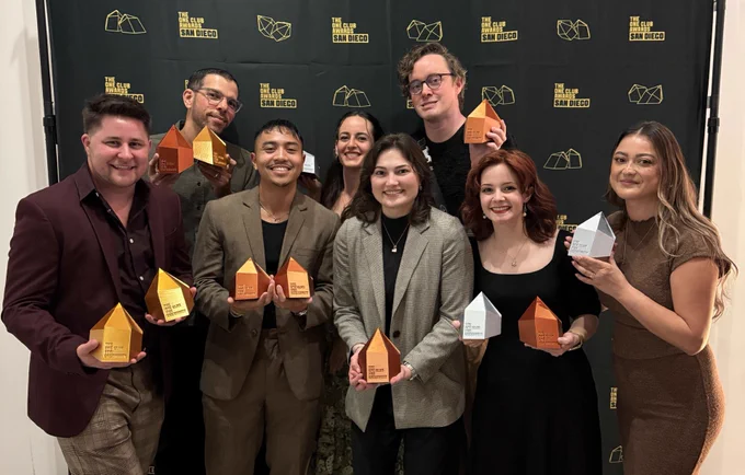 Eight people hold up gold and silver design awards