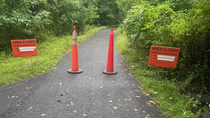 Orange cones and signs with the words "area closed" to announce an area of trailway closed to pedestrians. 