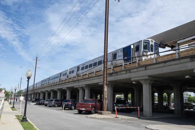 An exterior view of Babylon Station with a train pulling into the station.