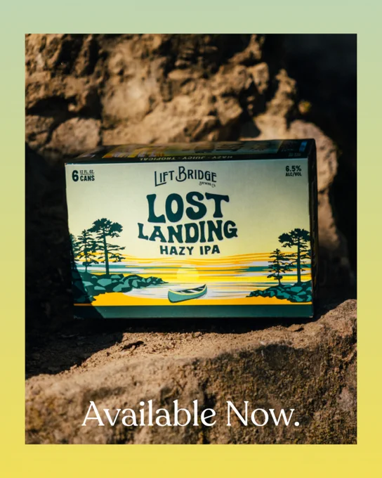 A box of Lost Landing Hazy IPA beer is positioned on a rock with text indicating its availability. The image has a natural and rugged backdrop, enhancing the adventurous theme.