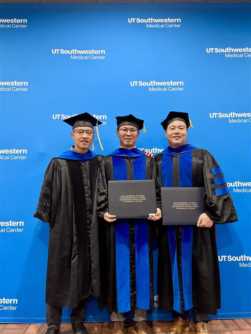Two graduates with a faculty member.